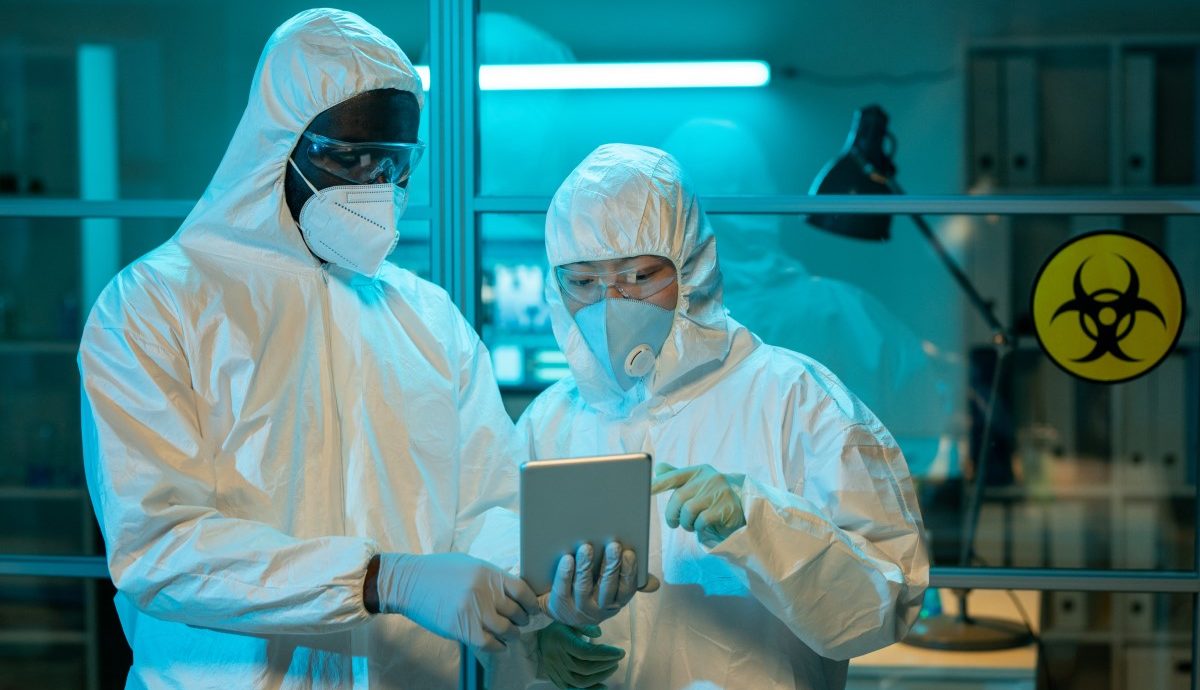 Two workers of scientific laboratory discussing online clinical data describing results of new experiment or research
